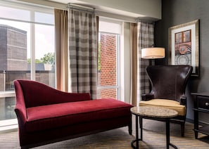 A modern living room with a red sofa, a small round table, and a dark leather armchair.