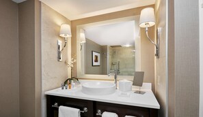 A modern bathroom with a large mirror, a white sink, and two wall-mounted lights.