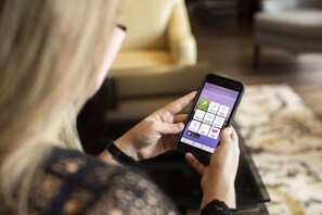 A person using a smartphone in a room with a sofa and a patterned rug.