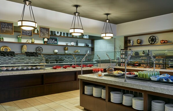 A buffet setup with various food items, a clock, and decorative items on shelves.
