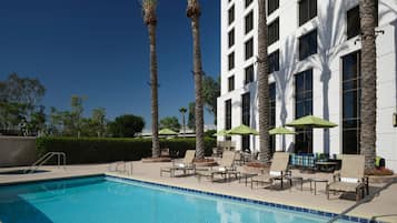 Una piscina al aire libre, sombrillas, tumbonas