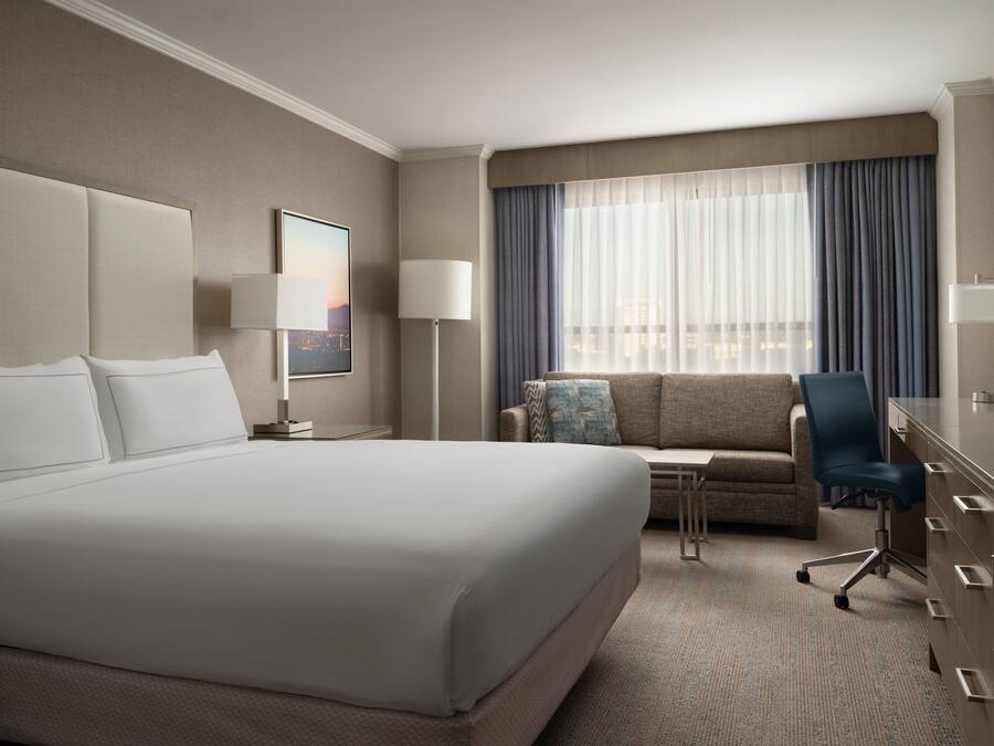 Una habitación de hotel con una cama grande, un sofá, un escritorio y una silla.