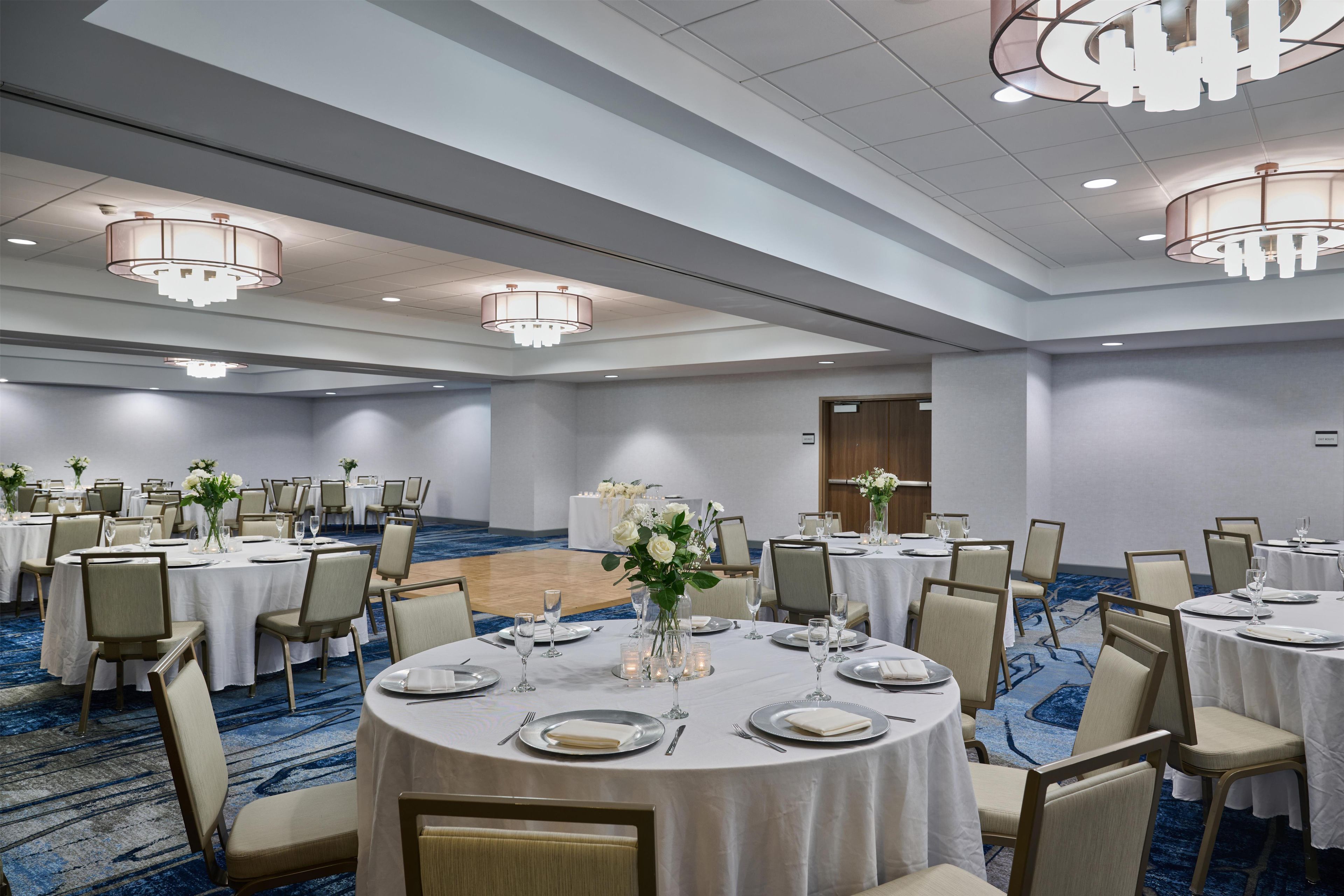 Un salón de banquetes con mesas redondas, sillas y candelabros.