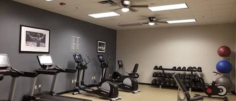 A gym with treadmills, elliptical machines, and weightlifting equipment.