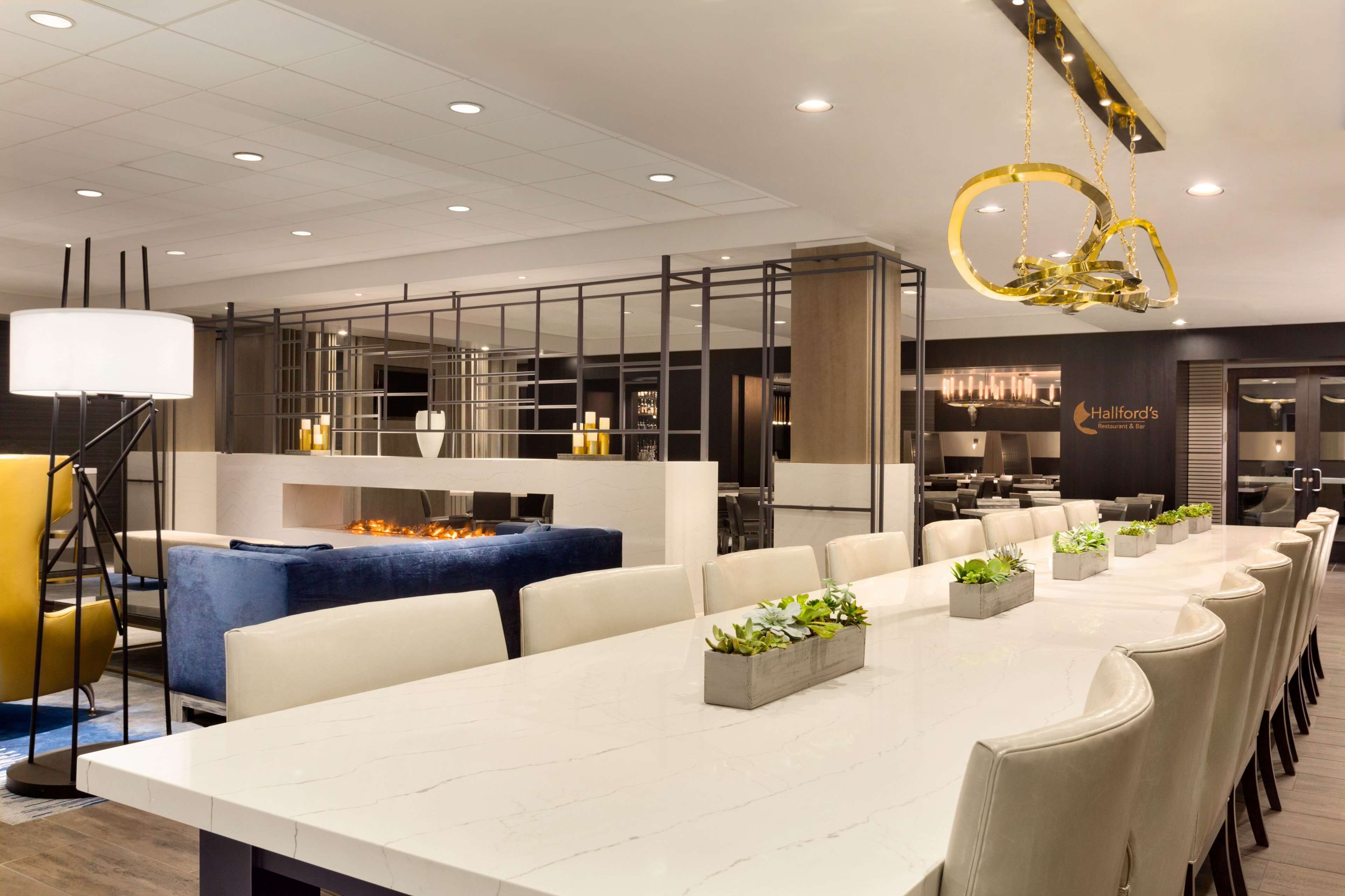 A modern conference room with a long table, white chairs, and a decorative chandelier.