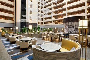 A multi-level hotel lobby with a central atrium, multiple seating areas, and a variety of tables and chairs. - Embassy Suites by Hilton Dallas DFW Airport North (Grapevine)
