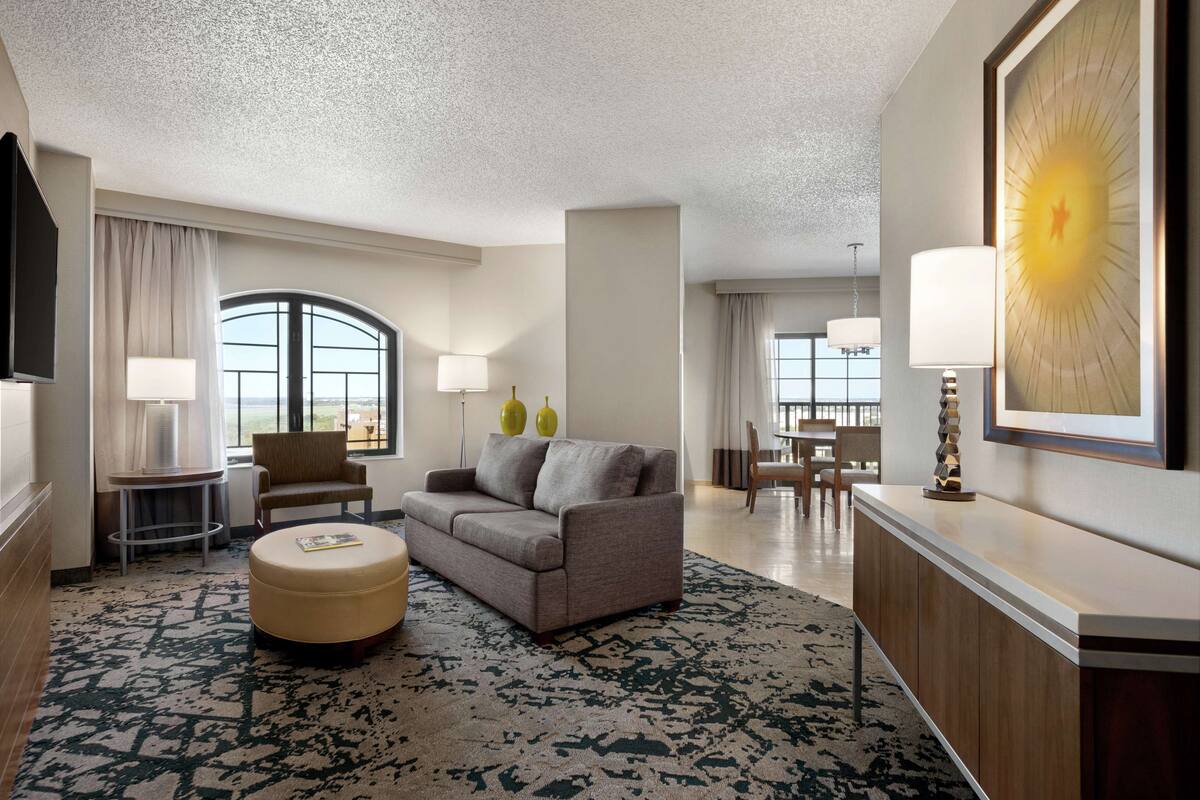 Een hotelkamer met een bank, een voetenbankje en een eethoek met een tafel en stoelen.