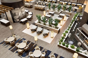 A spacious indoor area with multiple seating arrangements, including tables and chairs, and a central water feature. - Embassy Suites by Hilton Dallas DFW Airport North (Grapevine)
