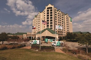 A large hotel with multiple floors, a flag, and a sign indicating it's an Embassy Suites hotel. - Embassy Suites by Hilton Dallas DFW Airport North (Grapevine)
