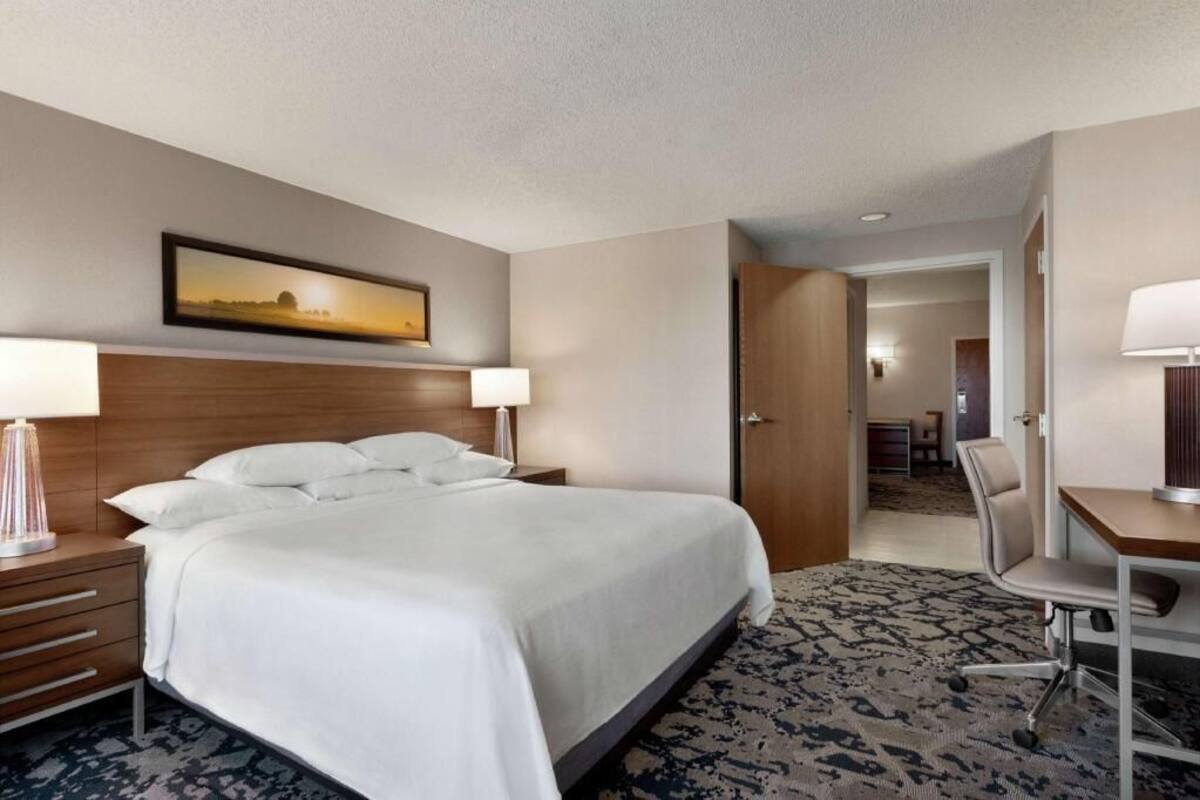 Een hotelkamer met een groot bed, nachtkastjes, een bureau en een stoel.