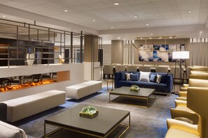 Un hall d’hôtel moderne doté d’un espace salon, d’une cheminée et d’un coin repas.