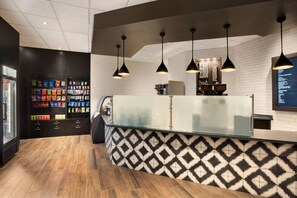 A modern coffee shop interior with a counter, hanging pendant lights, and a menu board.