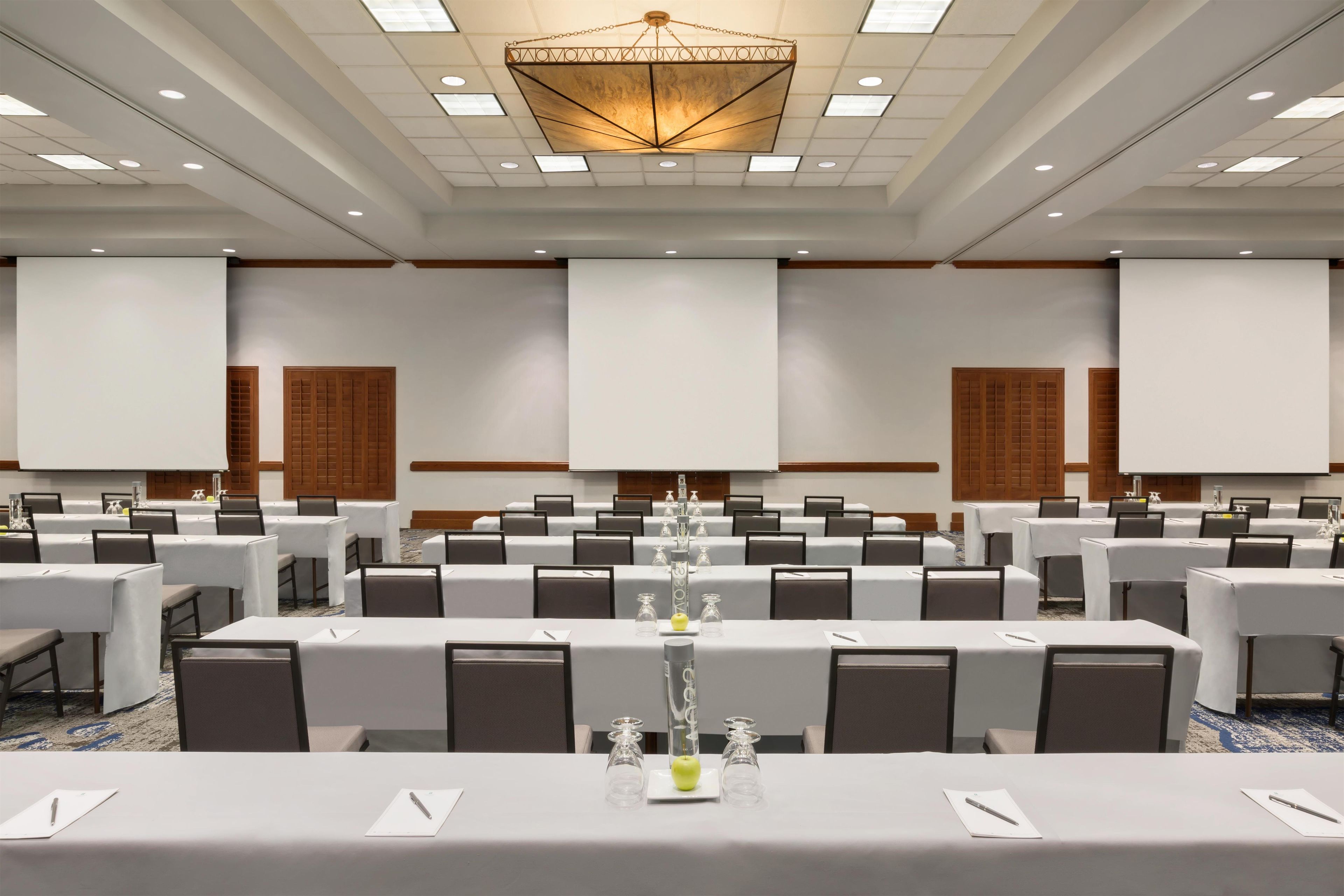 Une salle de conférence équipée de plusieurs tables, de chaises et d’un grand écran.