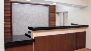 A reception area with a wooden panel wall, a black reception desk, and a tiled floor. - Fairfield Inn & Suites Dayton South (Dayton)