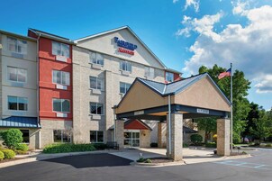 Un hotel Fairfield Inn & Suites by Marriott con entrada cubierta, aparcamiento y cielo despejado.