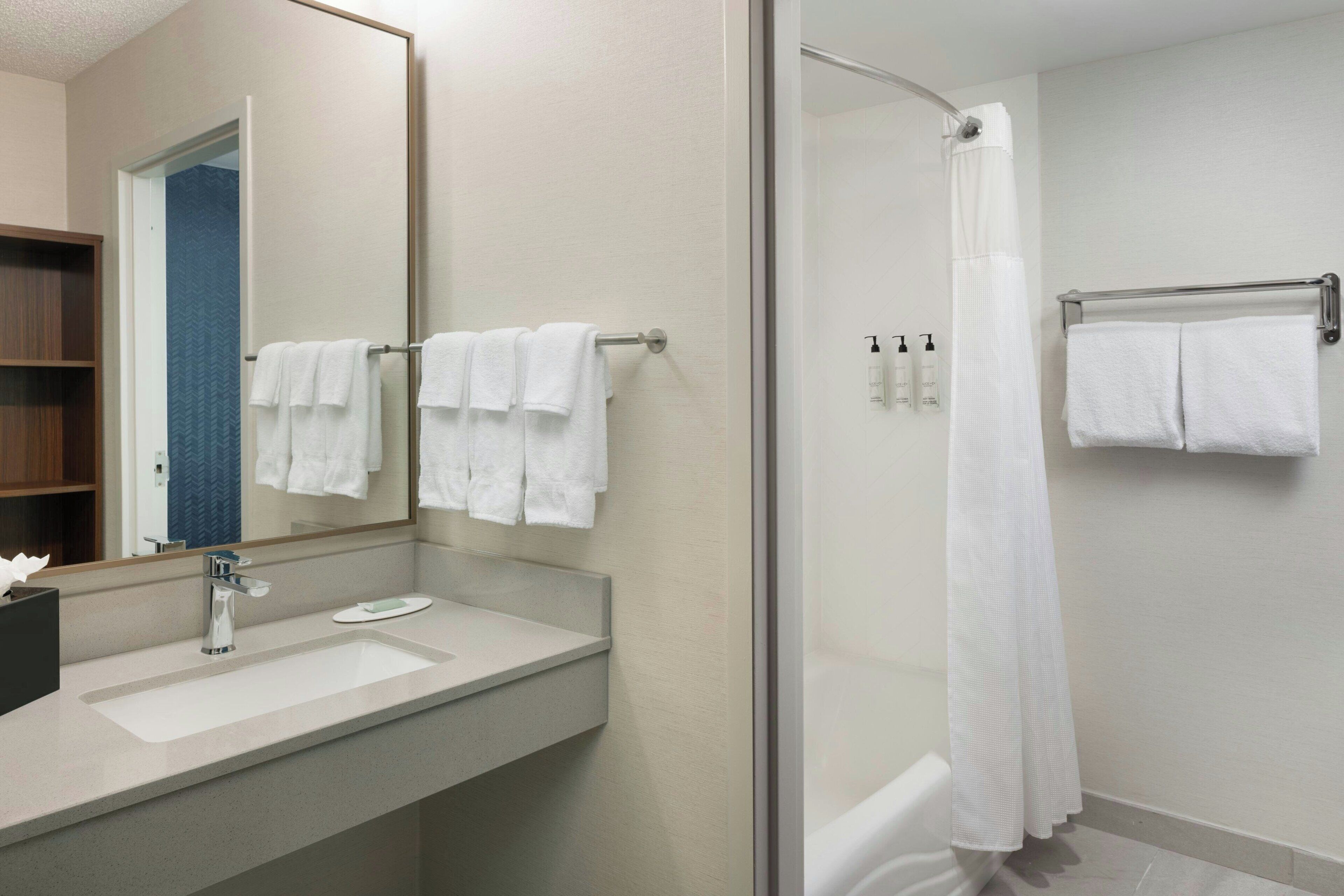 A modern bathroom with a large mirror, a sink, and a shower area.