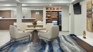 A hotel lobby with a reception desk, seating area, and a vending machine. - Fairfield Inn & Suites Jacksonville Airport (Jacksonville)