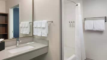 Um banheiro moderno com box de vidro, um espelho grande e uma pia branca.