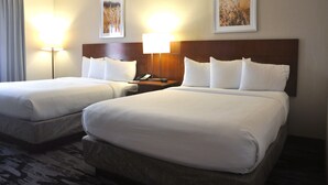 A hotel room with two beds, a wooden headboard, a nightstand with a phone, and two wall-mounted lamps. - Fairfield Inn & Suites Jacksonville Airport (Jacksonville)