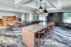 A modern hotel lobby with a central bar area, seating arrangements, and a large window providing natural light. - Fairfield Inn and Suites by Marriott Frankenmuth (Frankenmuth)