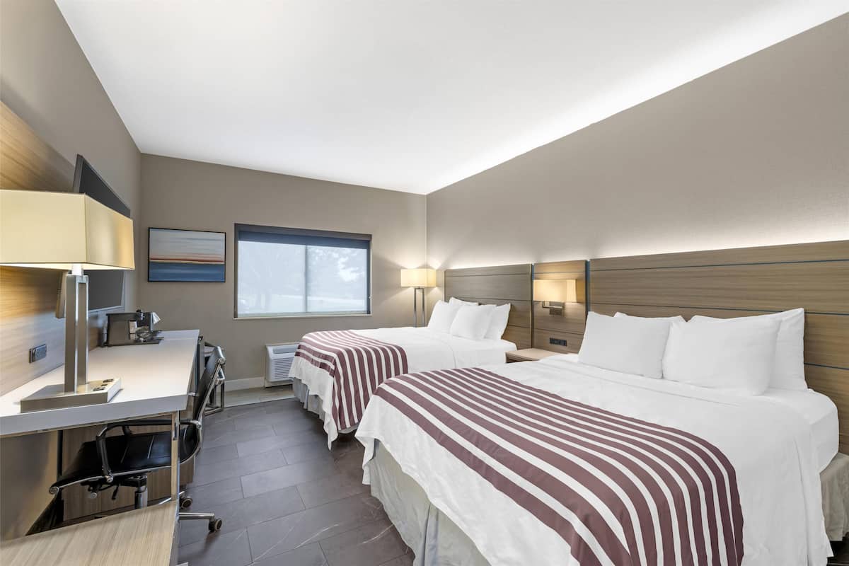Ein Hotelzimmer mit zwei Betten, einem Schreibtisch und einem Stuhl.