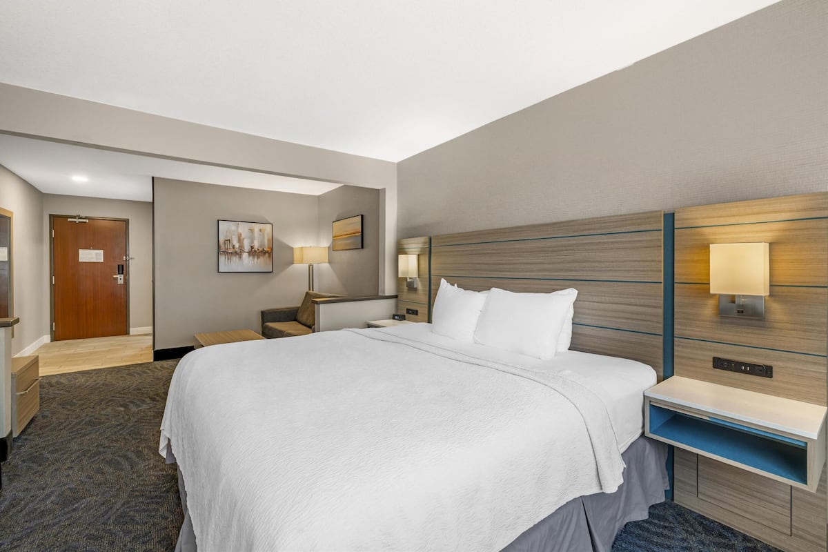 Ein Hotelzimmer mit einem großen Bett, einem Nachttisch, einem Schreibtisch und einer Wandlampe.