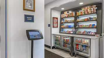 A self-service kiosk and refrigerated beverage dispensers in a hotel lobby.