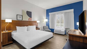 Una habitación de hotel moderna con una cama grande, dos mesitas de noche con lámparas, un televisor de pantalla plana, un escritorio y una silla.