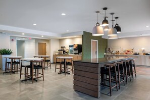 Une cuisine moderne dotée d’un îlot central, de tabourets de bar, de luminaires suspendus et de divers appareils électroménagers.