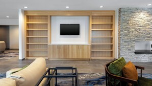 Een moderne woonkamer met een ingebouwde televisie, houten planken en een accentmuur van steen.
