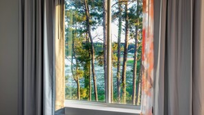 Een slaapkamer met een groot raam, gordijnen en een bed.