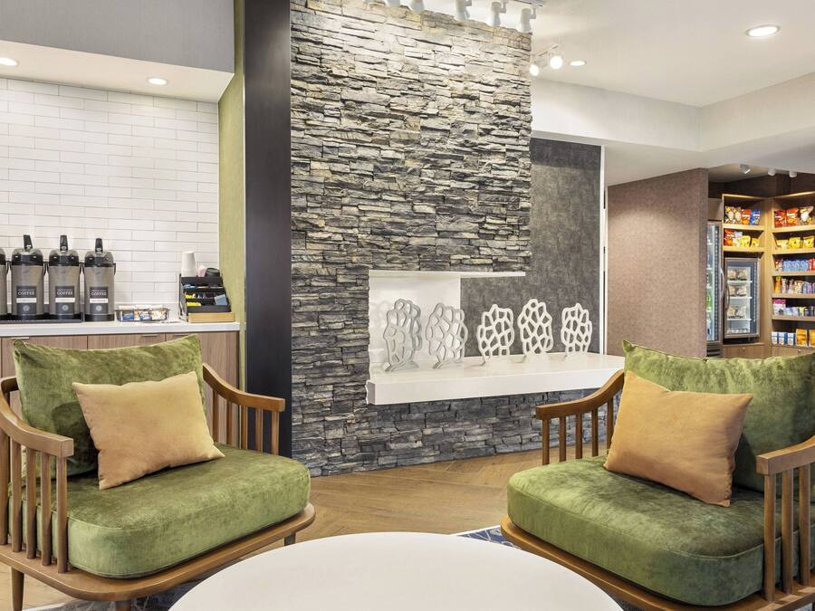 Un vestíbulo con pared de piedra, estación de café y barra de aperitivos.