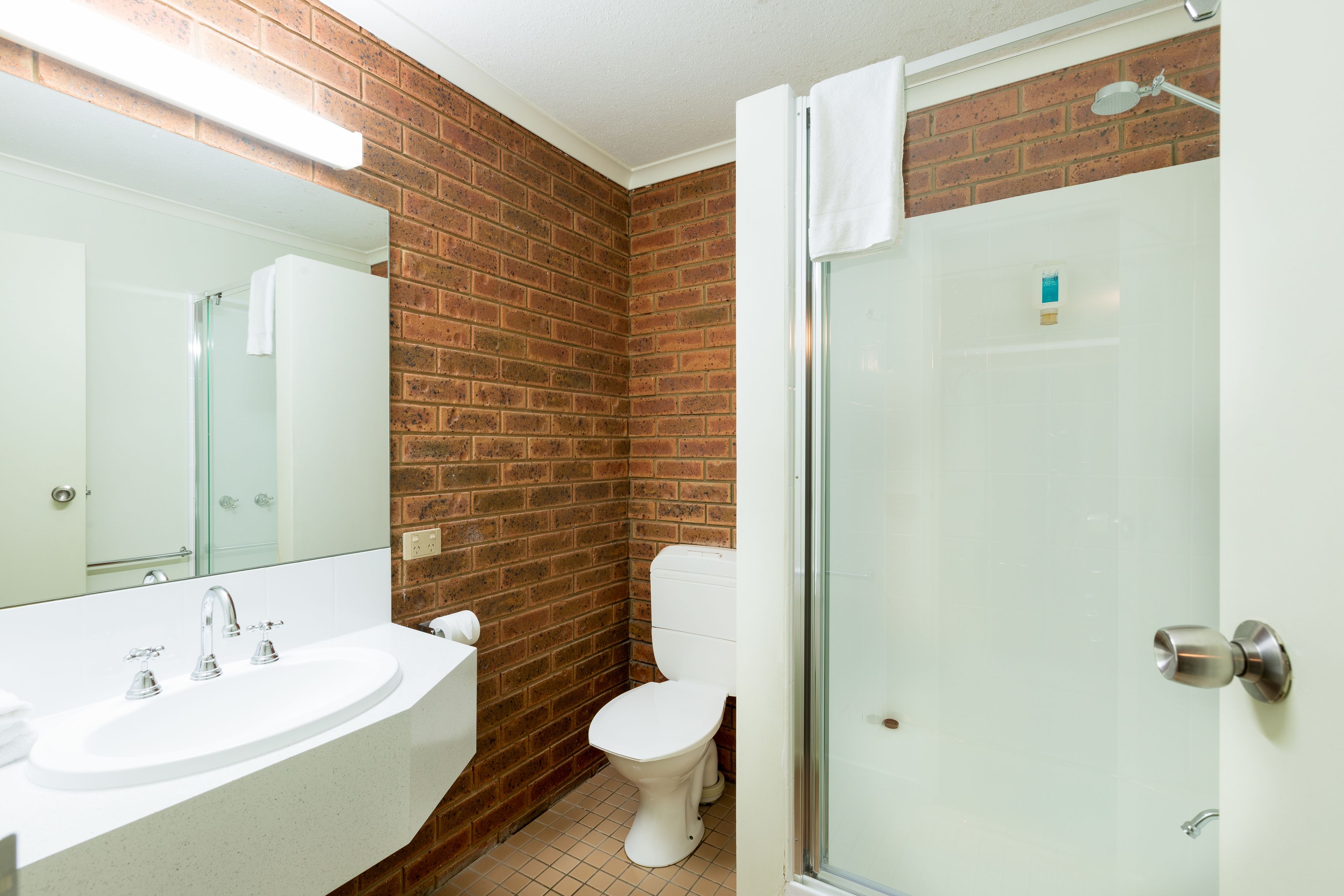 Un baño con un lavamanos blanco, un inodoro y una cabina de ducha de vidrio.