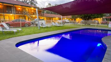 Una piscina al aire libre, sillones reclinables de piscina