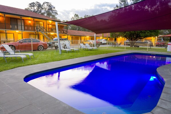 Una piscina al aire libre, sillones reclinables de piscina