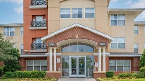 A multi-story building with a central entrance, a lobby area, and a numbered address. - Extended Stay America Suites Columbia Columbia Corporate Pk (Columbia)