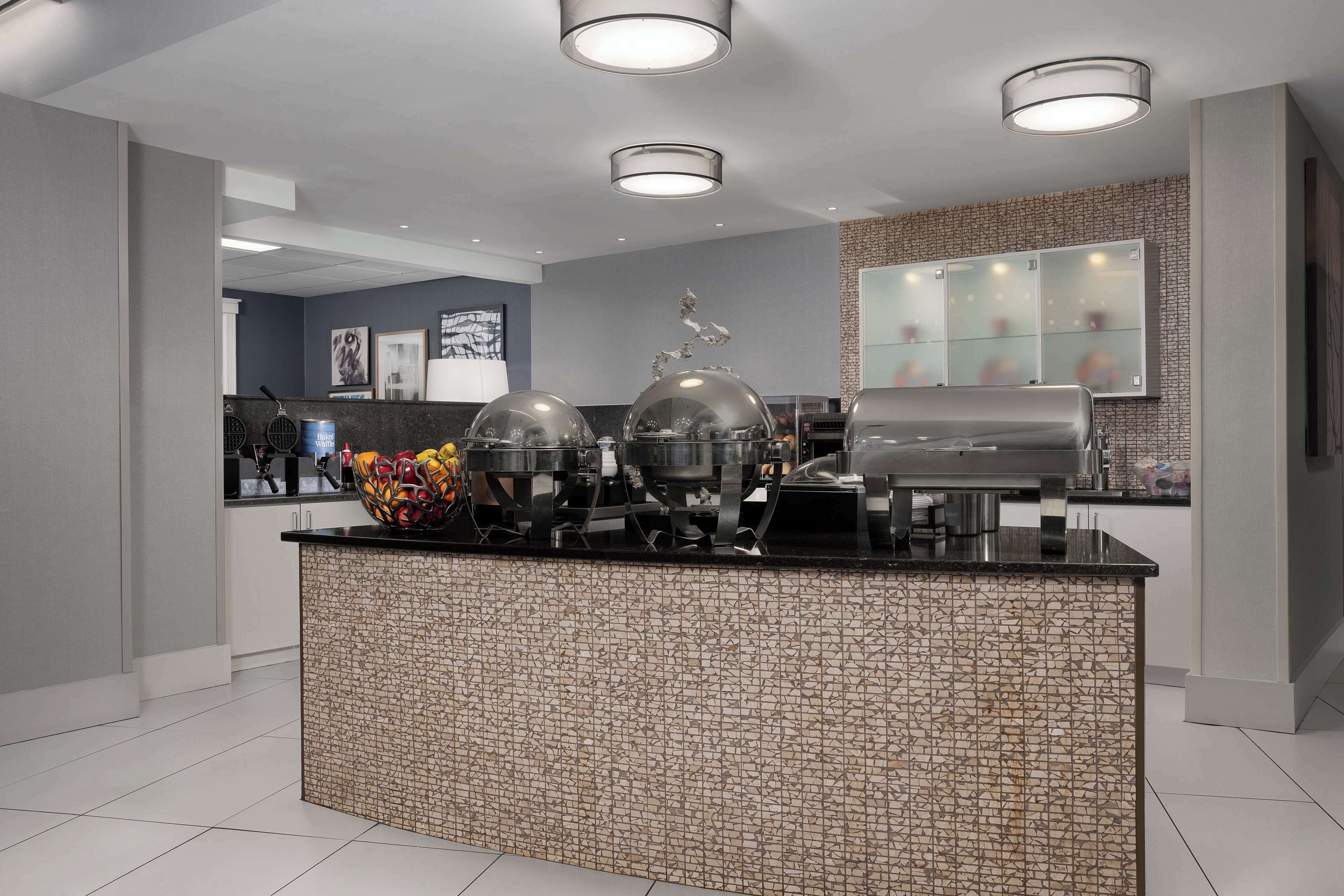 A modern kitchen area with a central island, overhead lighting, and a backsplash.