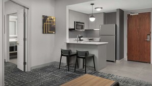 A modern kitchen with a microwave, refrigerator, and bar stools.