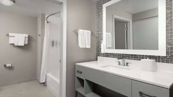 A modern bathroom with a shower, a large mirror, and a vanity with a sink and storage.