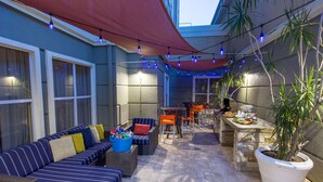 An outdoor patio area with a sofa, chairs, a table, and string lights.