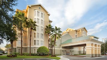 Classic hotel with a green roof, surrounded by lush landscaping and a covered entrance.
