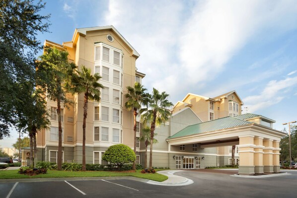 A multi-story hotel with a beige facade, palm trees, and a green-roofed entrance. - Homewood Suites by Hilton Orlando-International Drive/Convention Center (Orlando)