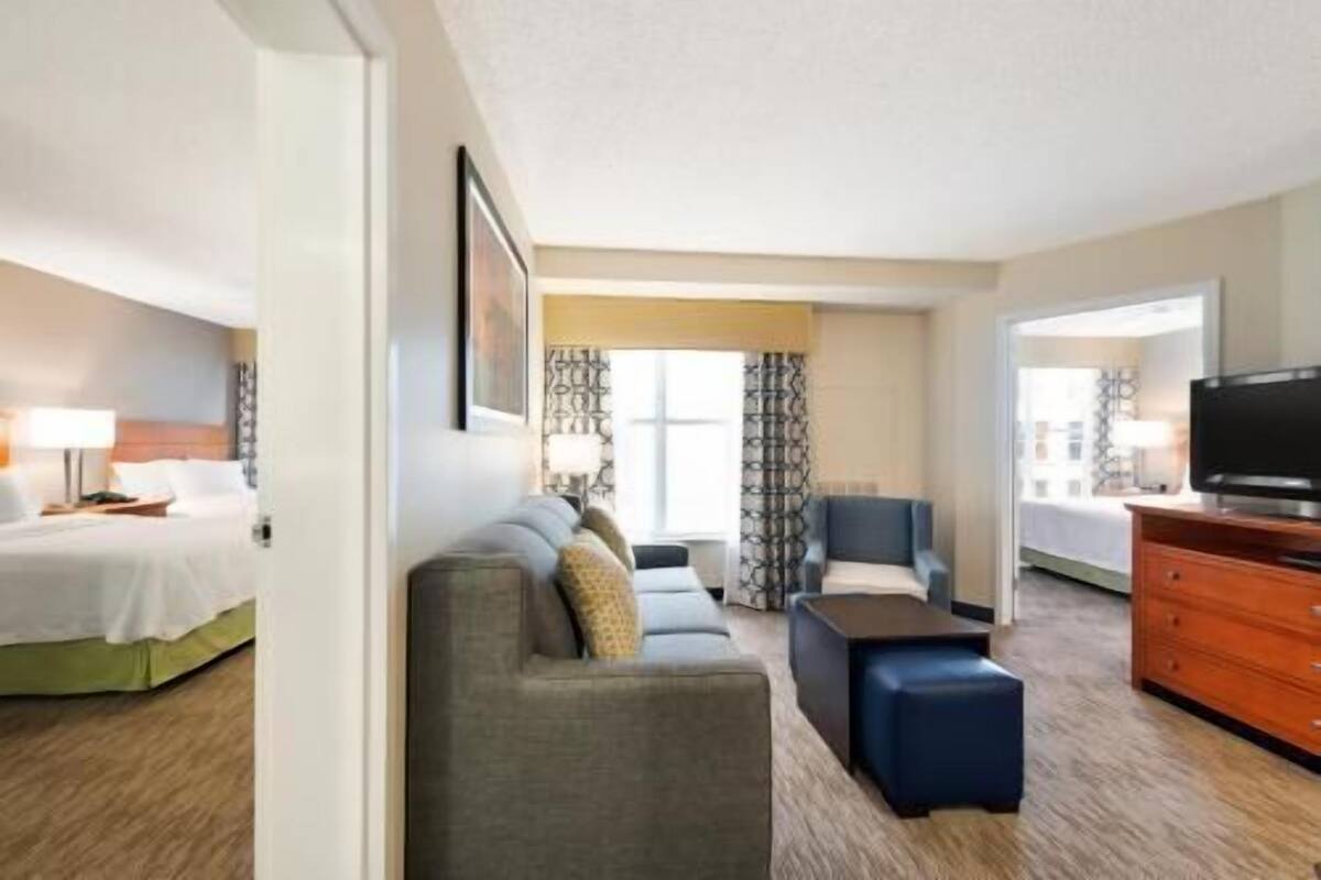 A hotel room with a bed, a sofa, a TV, and a dresser.