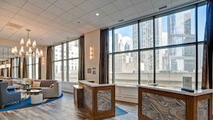 Un hall d’entrée spacieux, doté d’un comptoir d’accueil moderne, d’un coin salon confortable et de grandes fenêtres offrant une vue sur la ville.