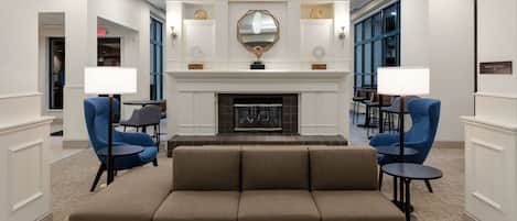 A lobby with a fireplace, a large mirror, and seating areas.