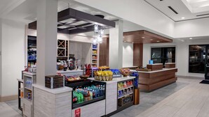 A modern hotel lobby with a reception desk, a beverage station, and a snack bar. - Hilton Garden Inn Atlanta Perimeter Center (Atlanta)