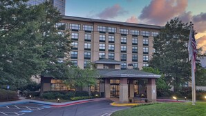 A multi-story hotel with a modern design, featuring a covered entrance and a flagpole. - Hilton Garden Inn Atlanta Perimeter Center (Atlanta)