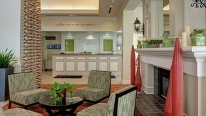 A lobby with a reception desk, seating area, and a fireplace. - Hilton Garden Inn Tulsa Airport (Tulsa)