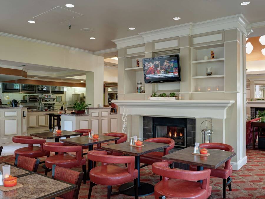 A restaurant with a fireplace, dining tables, and red chairs.