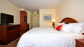 Una habitación de hotel con cama, televisión, escritorio y armario.